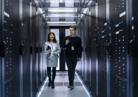 A man and a woman walk through a data center with servers