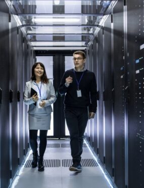 A man and a woman walk through a data center with servers