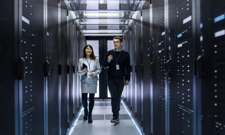 A man and a woman walk through a data center with servers