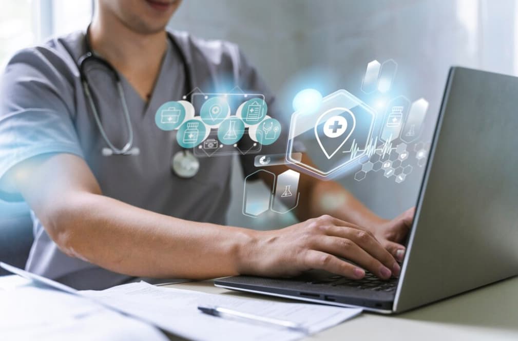 A male healthcare professional working with medical holograms on a laptop