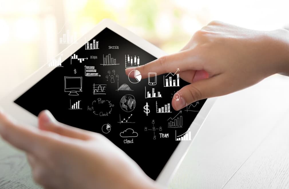 A hand interacting with business analytics icons on a tablet screen
