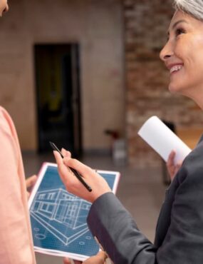 A woman smiles at a man while holding blueprints