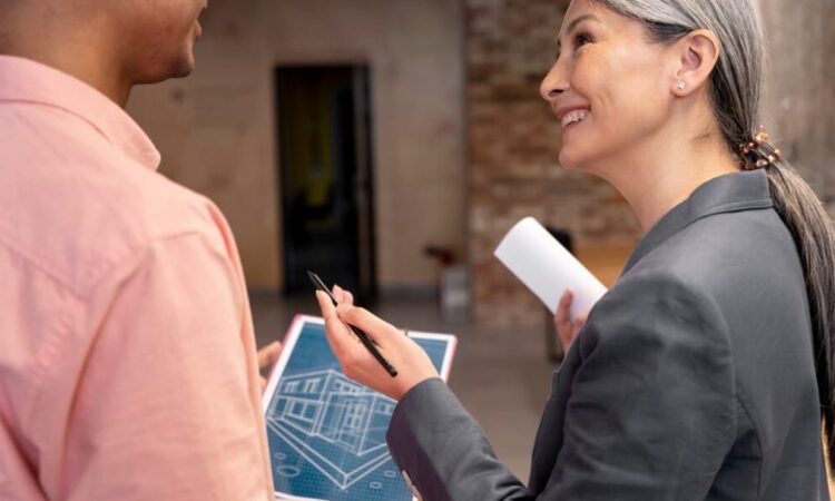 A woman smiles at a man while holding blueprints