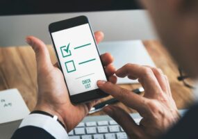 A person uses a smartphone app with a digital checklist marked on the screen