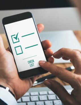 A person uses a smartphone app with a digital checklist marked on the screen