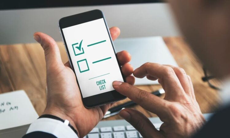 A person uses a smartphone app with a digital checklist marked on the screen